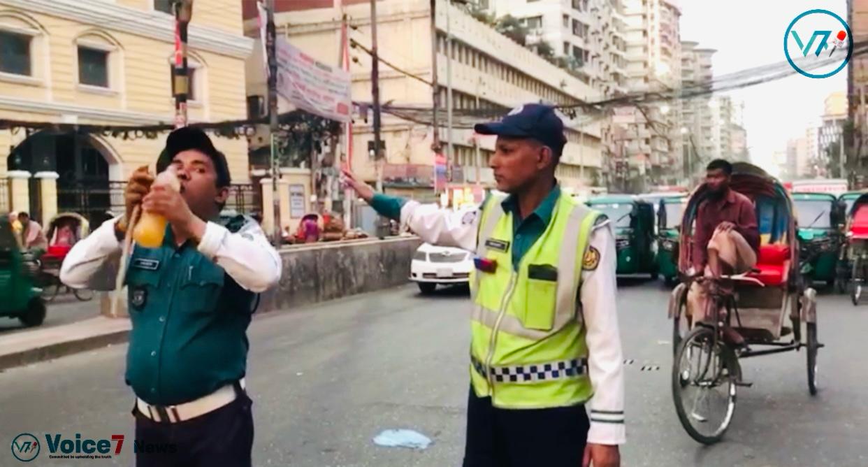 This photo was taken in Dhaka Bangla Motor Area. It shows traffic police holding an iftar and making a signal with another hand.